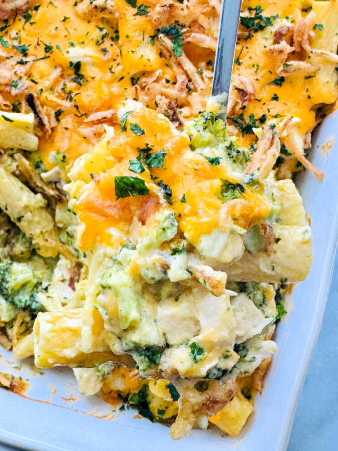 serving a spoonful of chicken broccoli pasta casserole from the baking dish