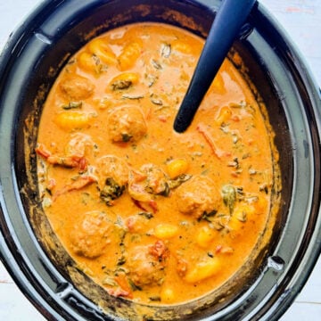 a slow cooker crock filled with marry me meatballs and gnocchi, ready to serve