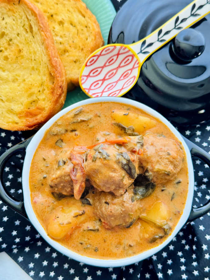 an individual crock filled with marry me meatballs and gnocchi with a side of garlic bread