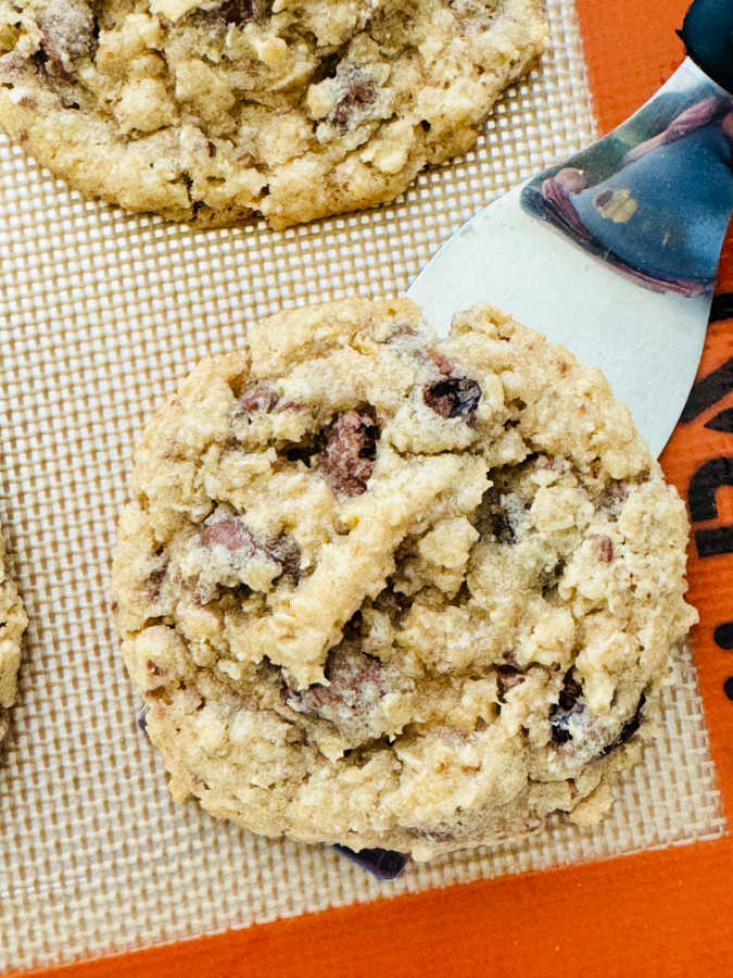using a spatula to remove one of the oatmeal cookies from the baking sheet