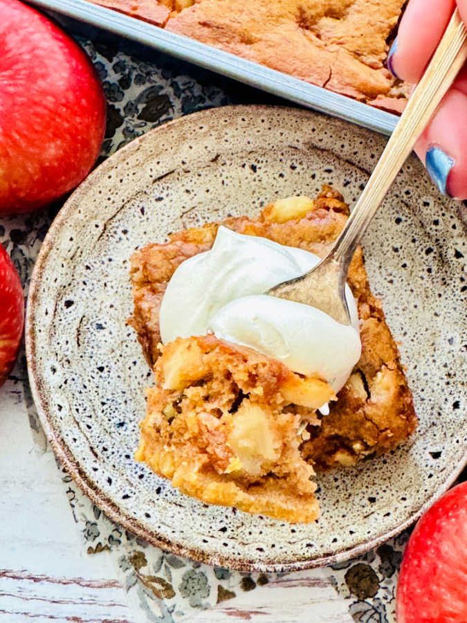 taking a bite of a sour cream apple square topped with cool whip