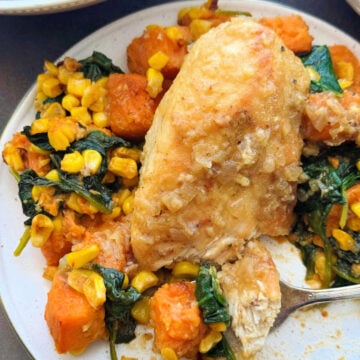 an apple cider glazed chicken breast plated with sautéed corn, sweet potatoes and spinach