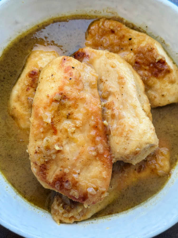 a bowl of cooked chicken breasts covered with apple cider glaze