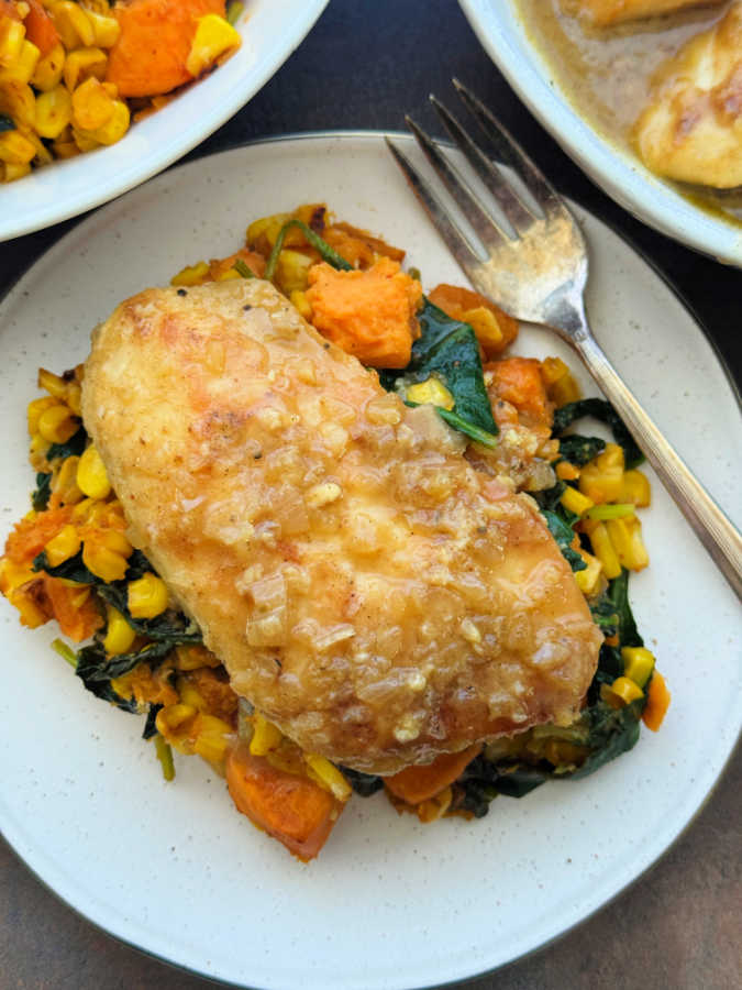 cooked chicken glazed with apple cider and plated with a mix of sweet potatoes, corn and spinach