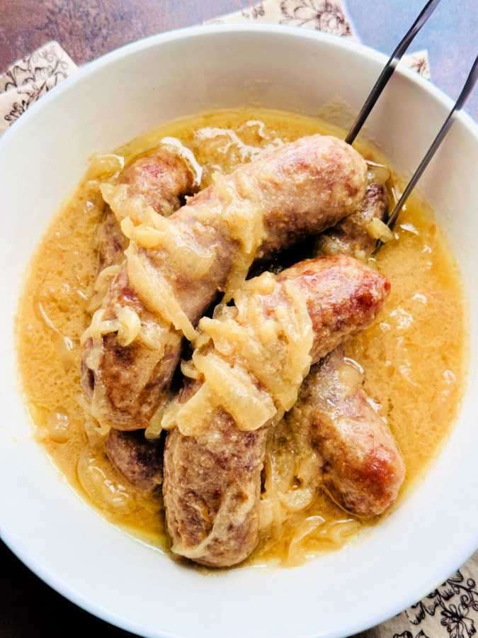 a bowlful of beer brats smothered in cooked onions
