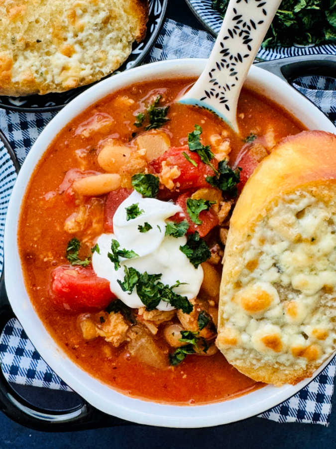 a crock full of buffalo chicken chili garnished with sour cream and cilantro
