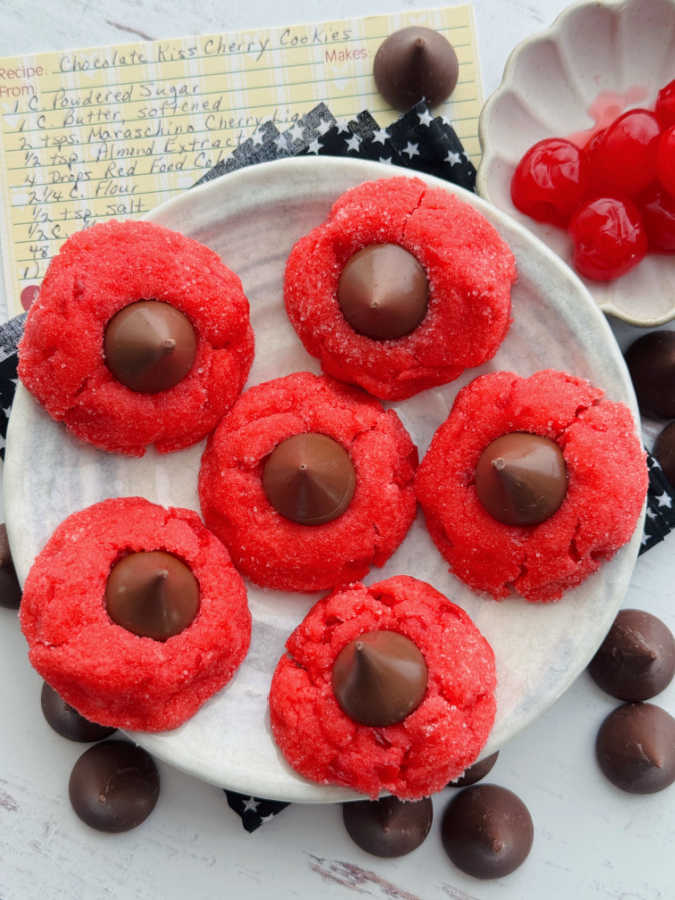 six cherry blossom cookies plated and surrounded by my mom's recipe cards and unwrapped Hershey kisses