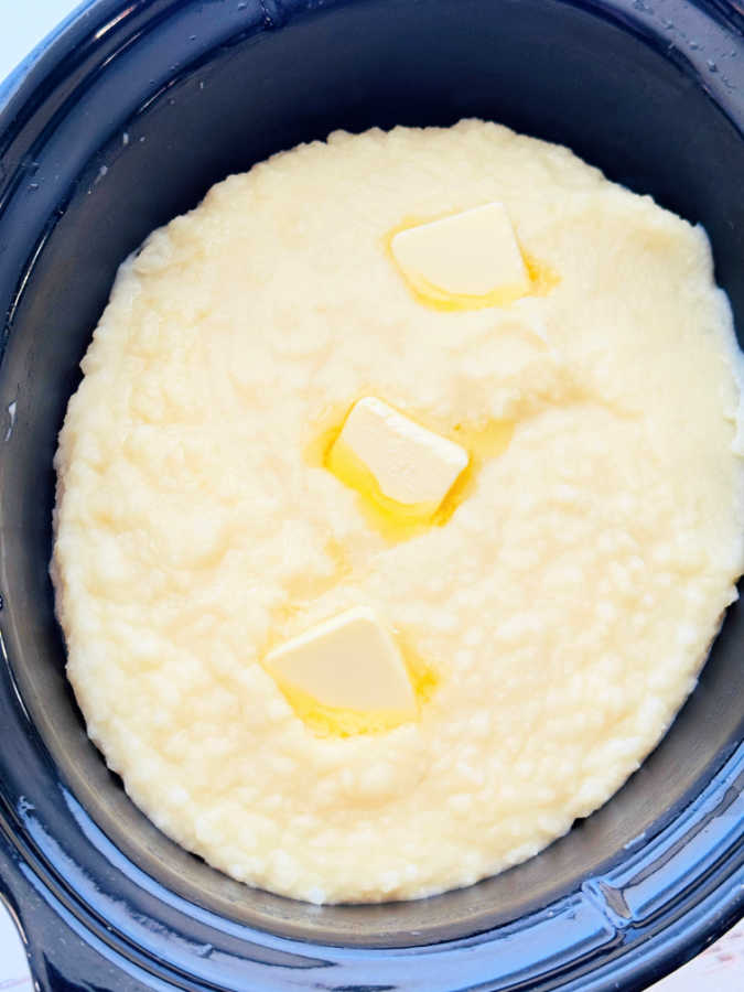 creamy crock pot mashed potatoes topped with pats of melting butter