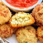 plated air fryer arancini with a bite taken out of one to show the interior