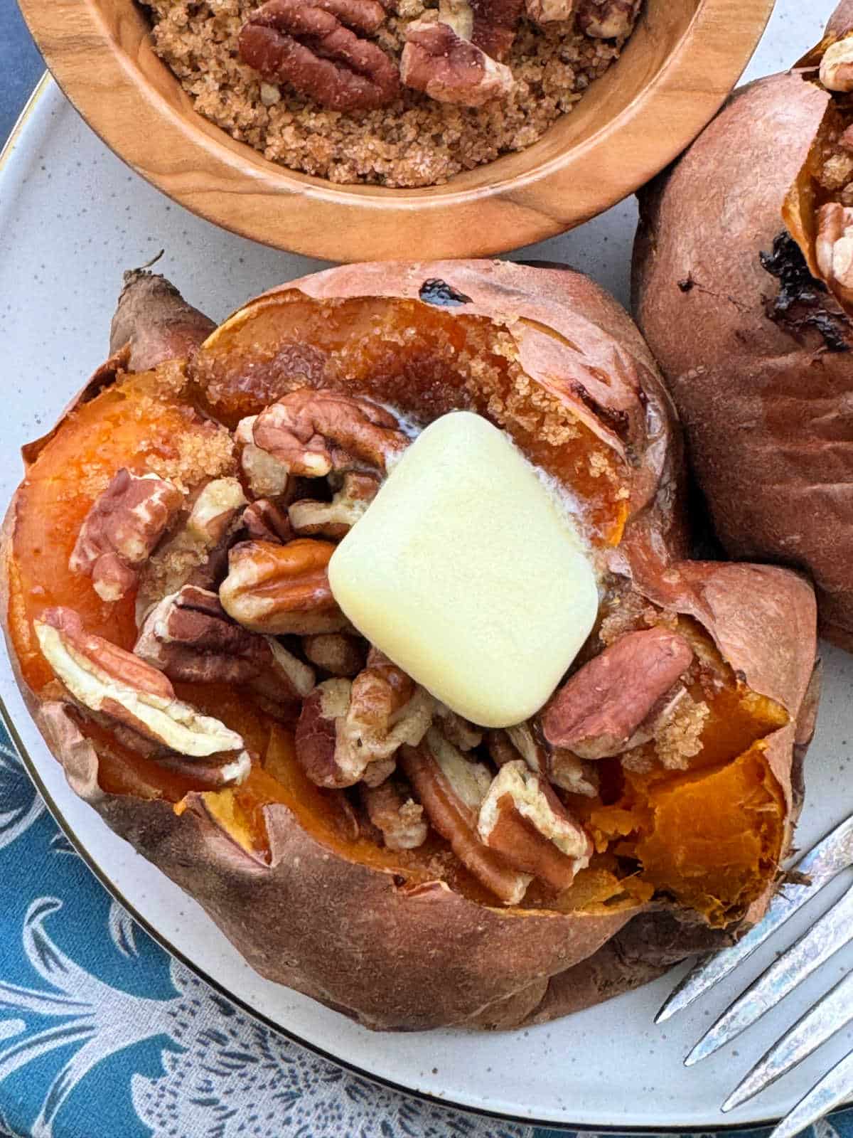 plated roasted sweet potato topped with brown sugar, pecans and butter