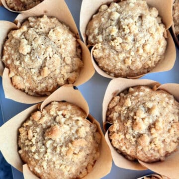 close up picture of four freshly baked banana bread muffins in tulip style muffin liners