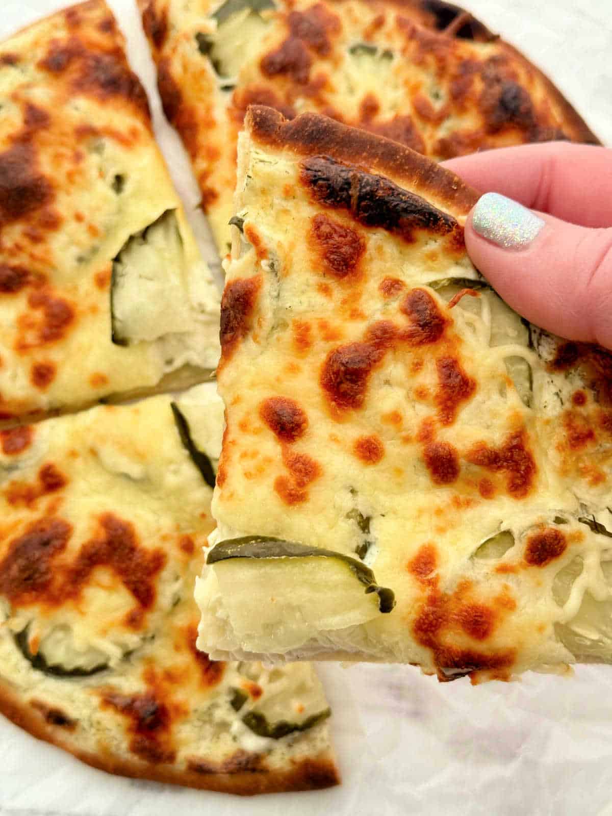 holding a slice of pickle pizza ready to take a bite