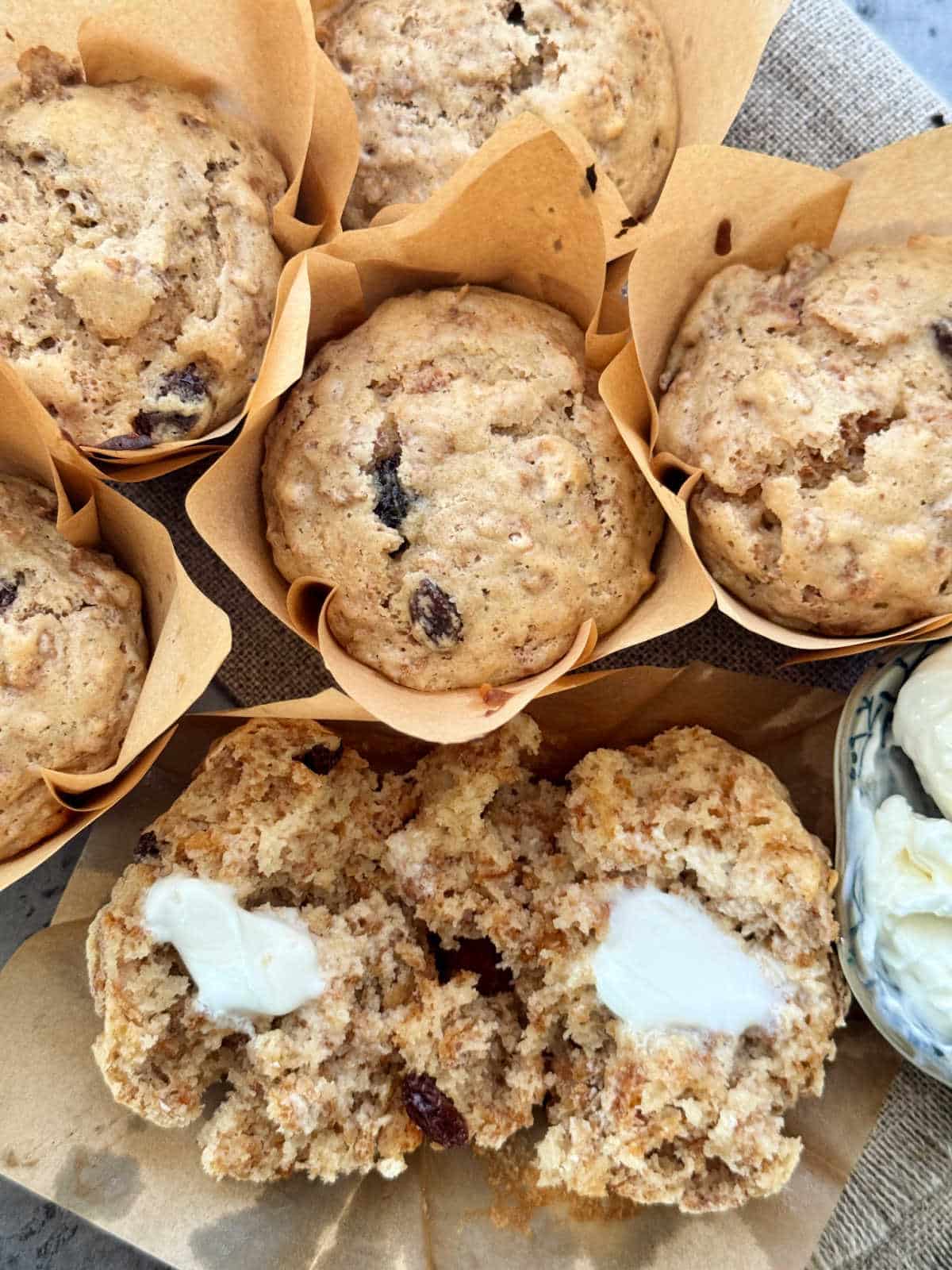 a grouping of freshly baked raisin bran muffins with butter for spreading