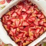 strawberry cobbler fresh out of the oven in a red ceramic square baking dish