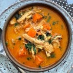 a bowl of mulligatawny soup garnished with chopped cilantro