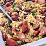 dishing a serving spoonful of sausage and rice casserole from the casserole dish