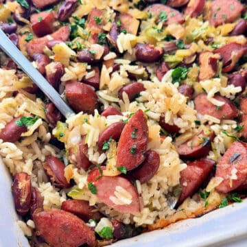 dishing a serving spoonful of sausage and rice casserole from the casserole dish