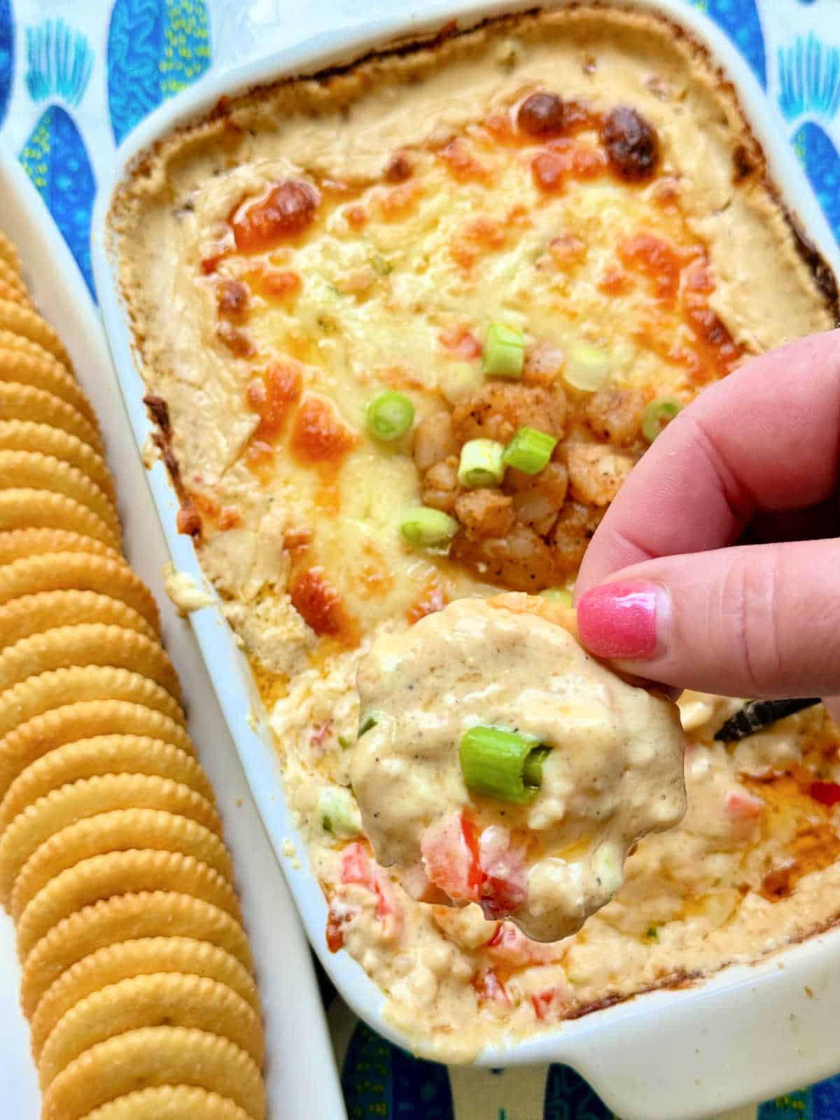 dipping a cracker into freshly baked cajun shrimp dip