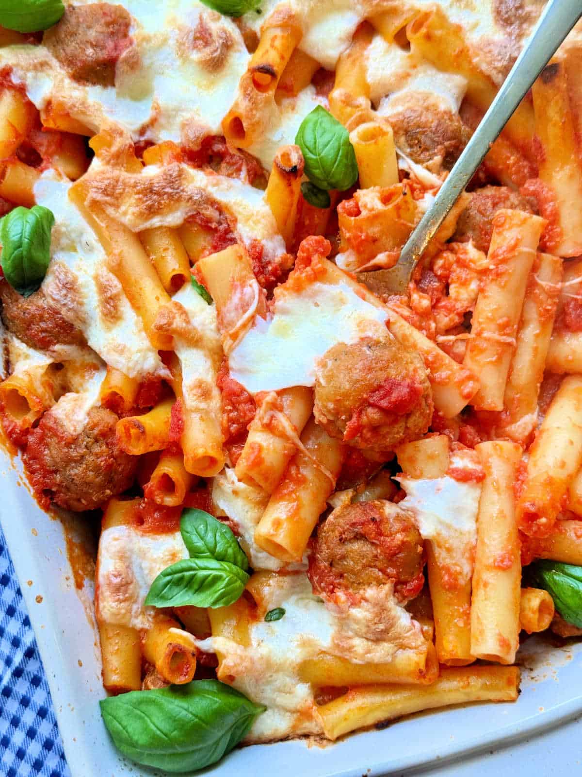 serving a spoonful of baked ziti from the baking dish