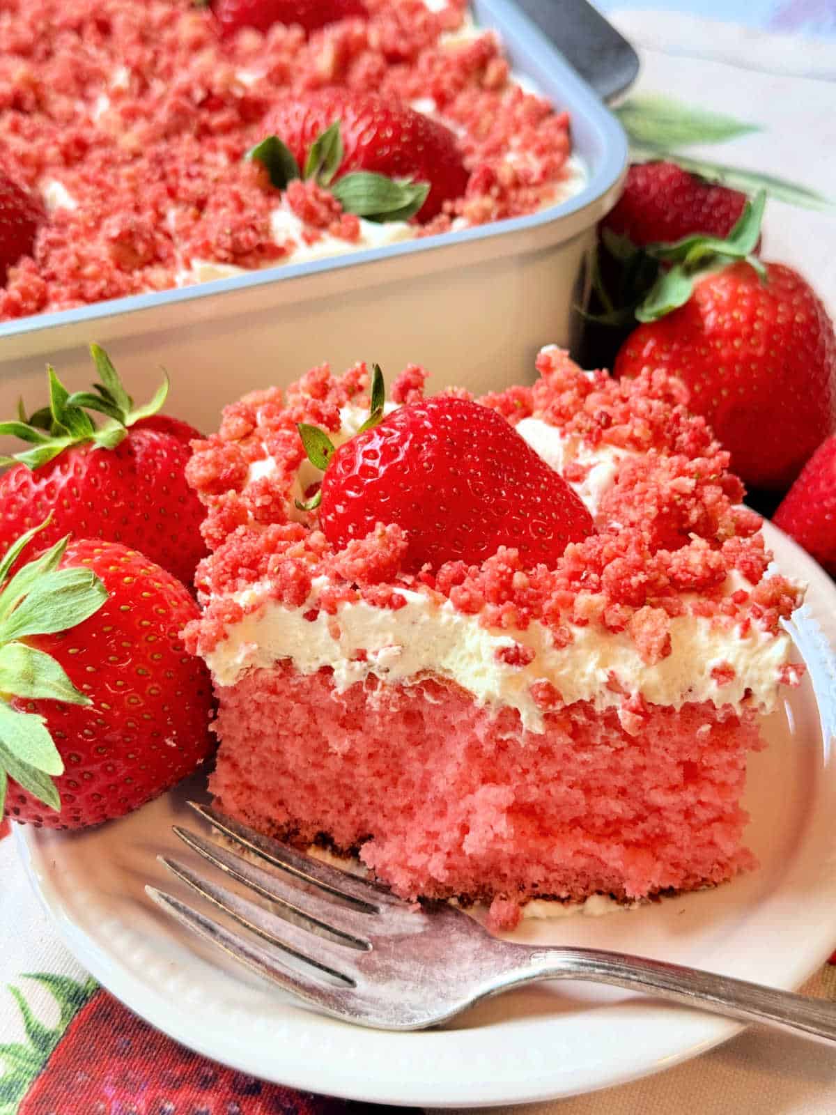 a slice of cake on a plate with a bite taken, and fresh strawberries around