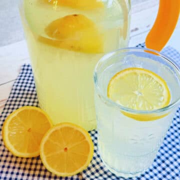 a glass of homemade lemonade beside a glass pitcher of lemonade