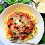 a bowlful of spaghetti bolognese garnished with Parmesan and basil