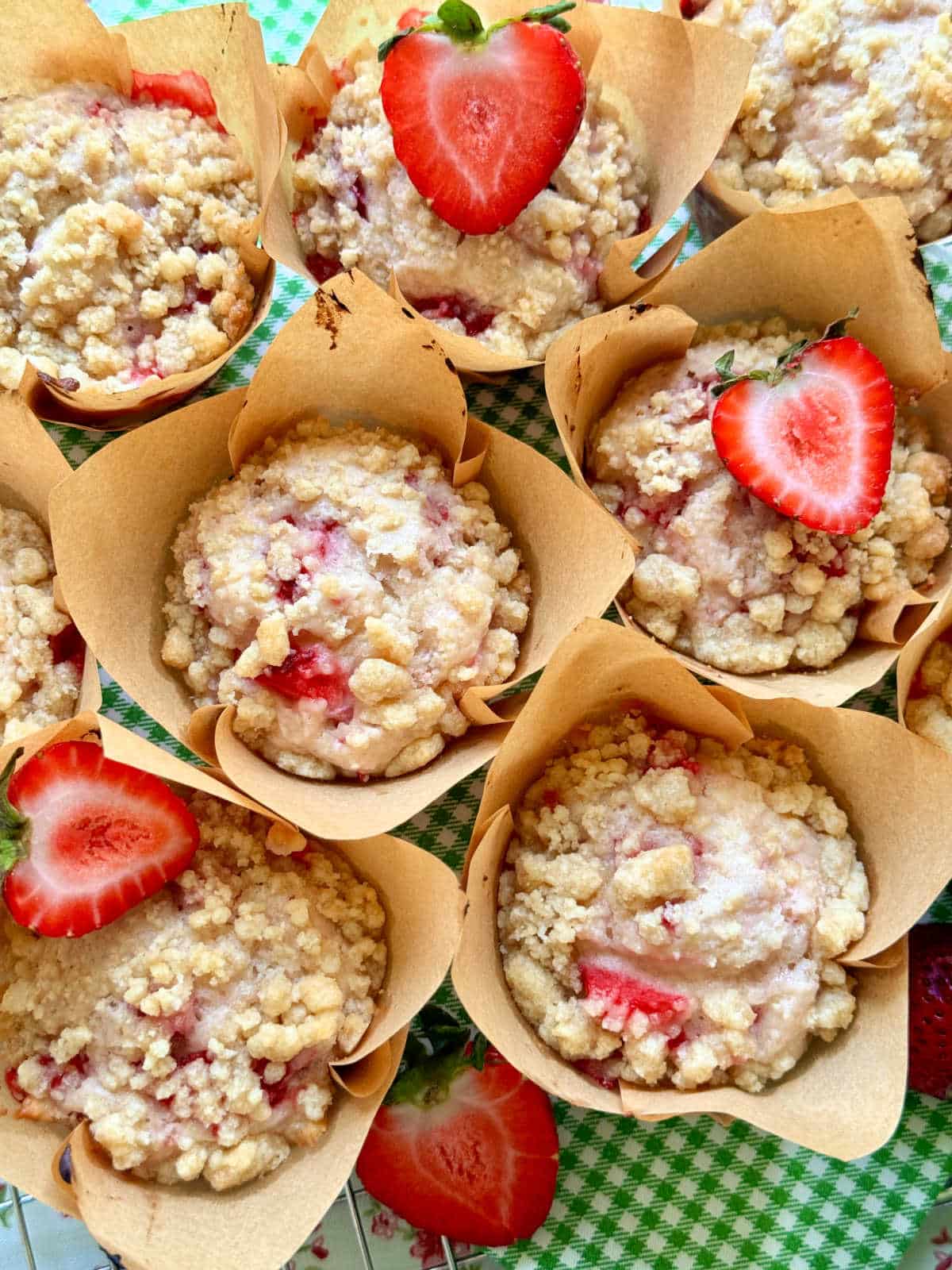 a group of strawberry muffins garnished with fresh strawberries sliced in half