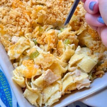 serving a spoonful of tuna noodle casserole from the baking dish