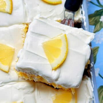 a slice of lemon poke cake being served from the pan