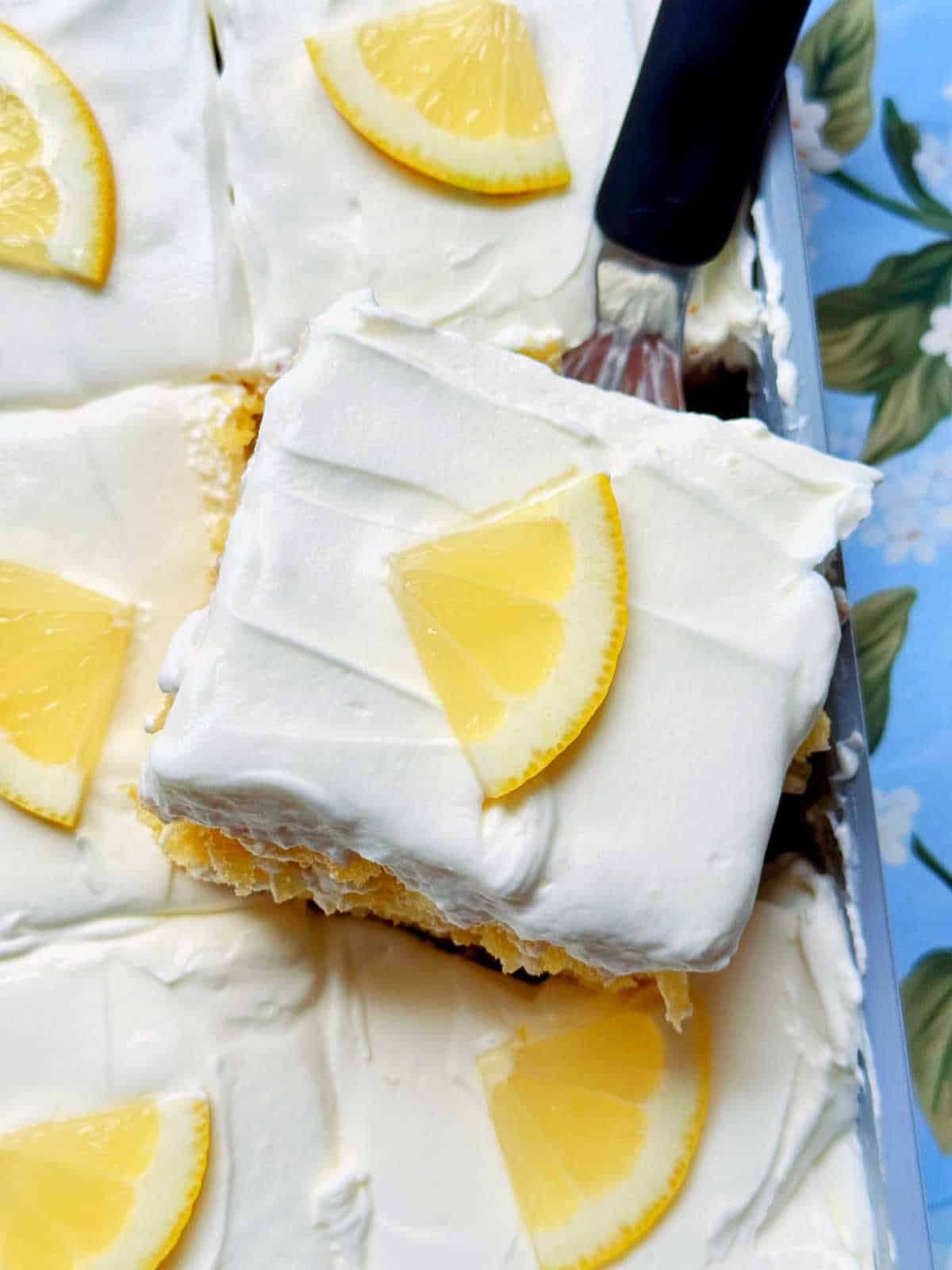 serving a slice of lemon poke cake from the pan