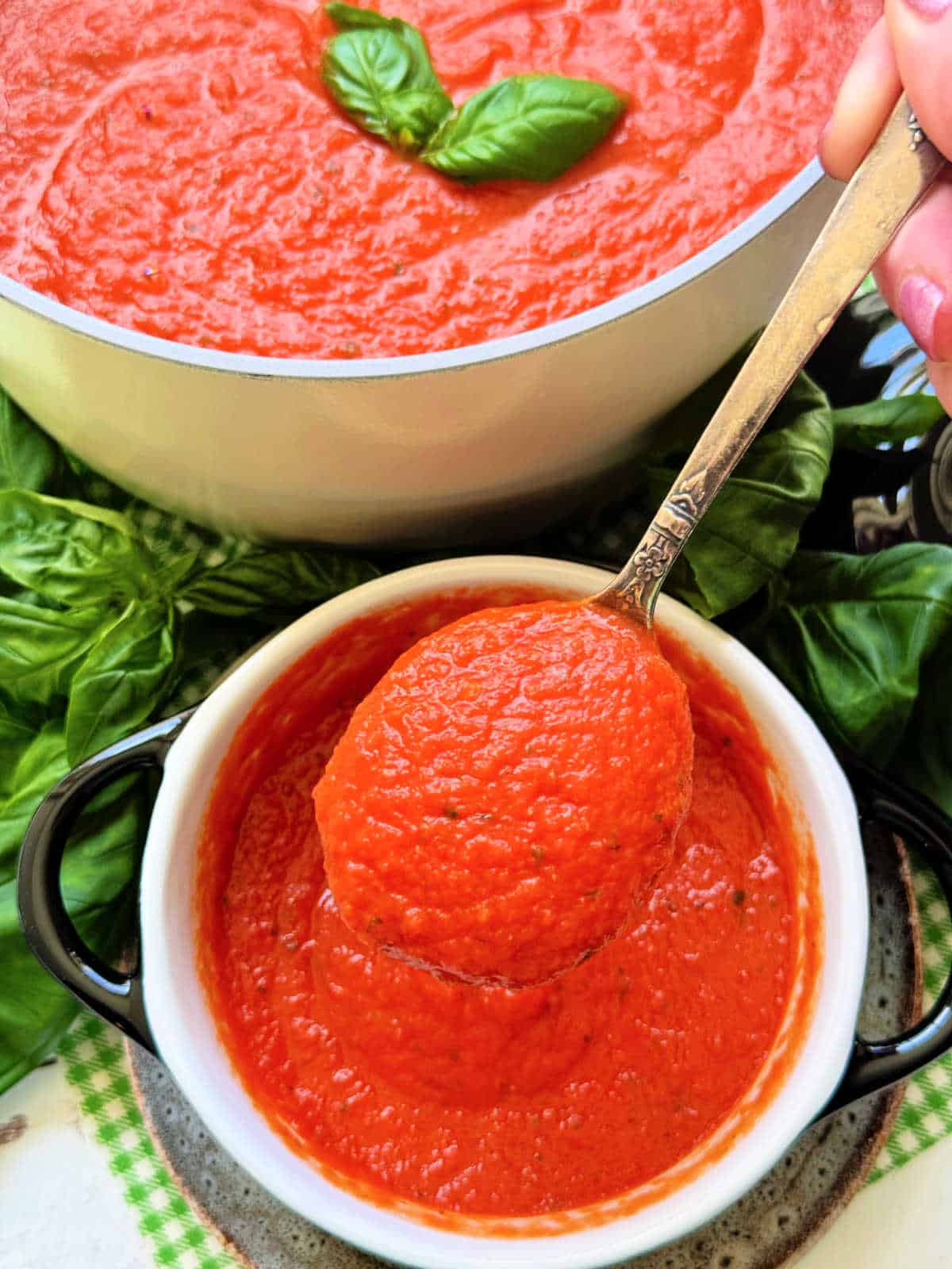 lifting a spoonful of tomato basil soup from its serving bowl