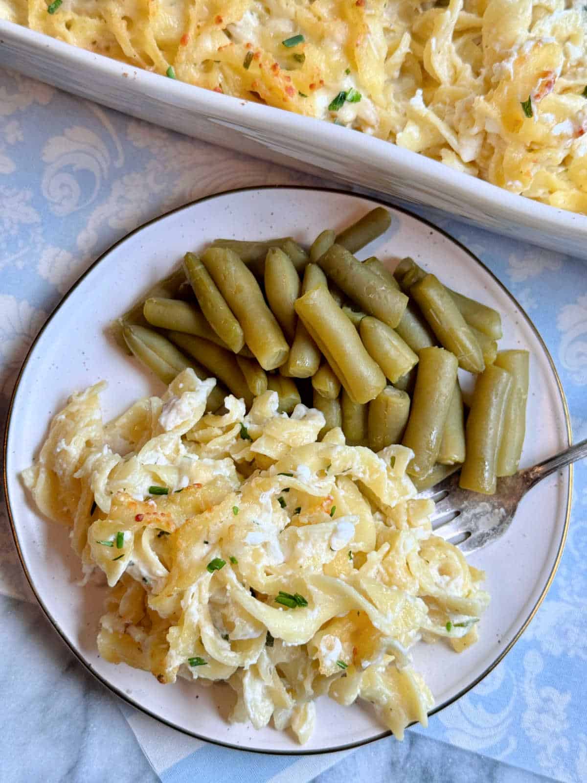 a plate of chicken ranch casserole with a side of green beans
