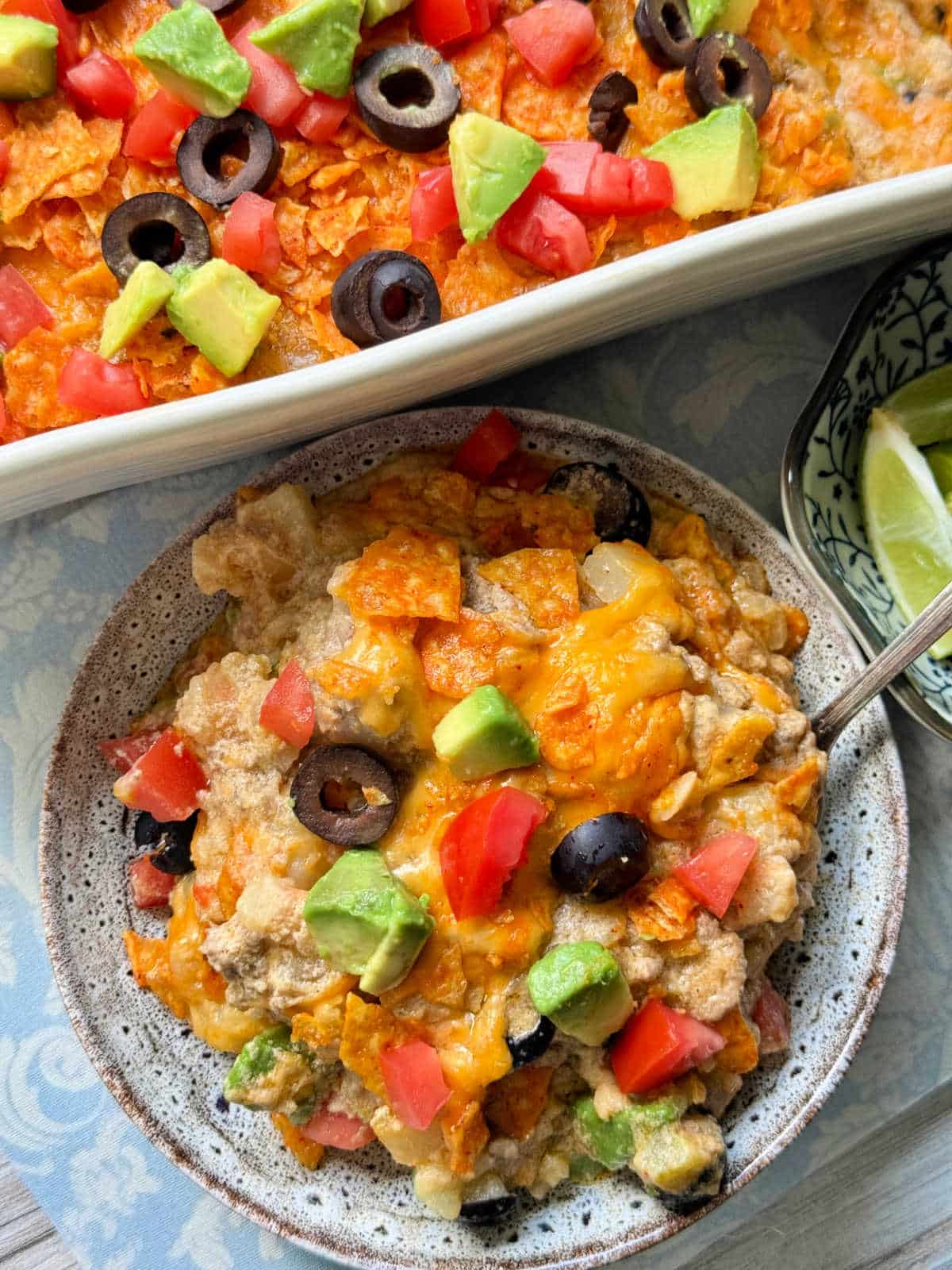 plated serving of taco hash brown casserole garnished with olives, tomatoes and avocado