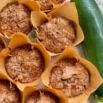 a dozen zucchini muffins displayed alongside a fresh zucchini