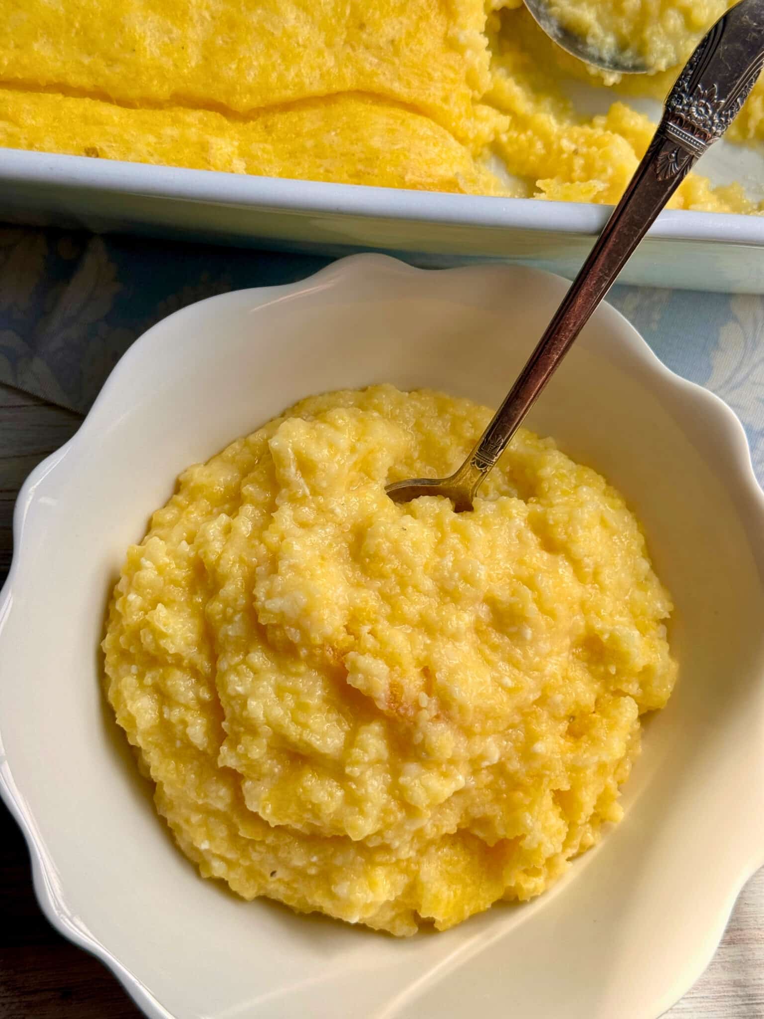 A serving dish of polenta sitting in front of its baking dish that it was served from