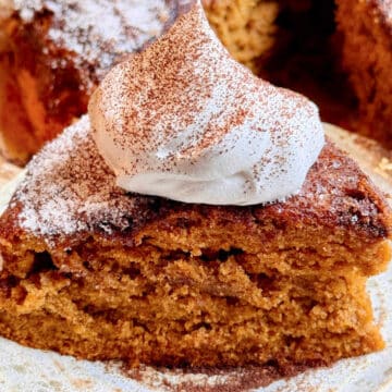 a slice of pumpkin spice latte cake topped with a dollop of whipped cream sprinkled with espresso powder
