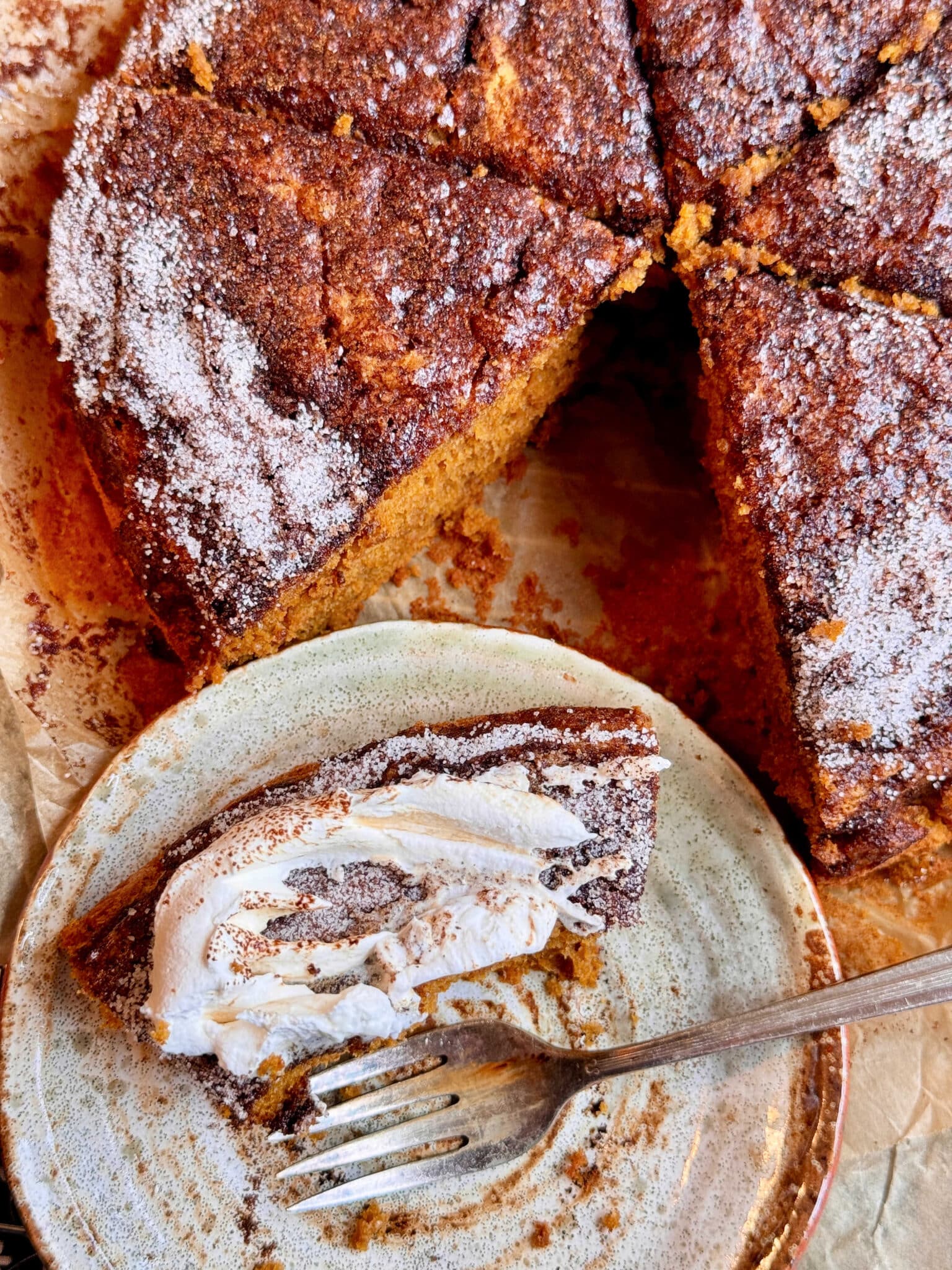 a half eaten slice of cake plated in front of the rest of the pumpkin spice latte cake