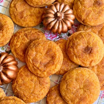 pumpkin spice cookies displayed on a wire cooling rack with some decorative small bronze pumpkins