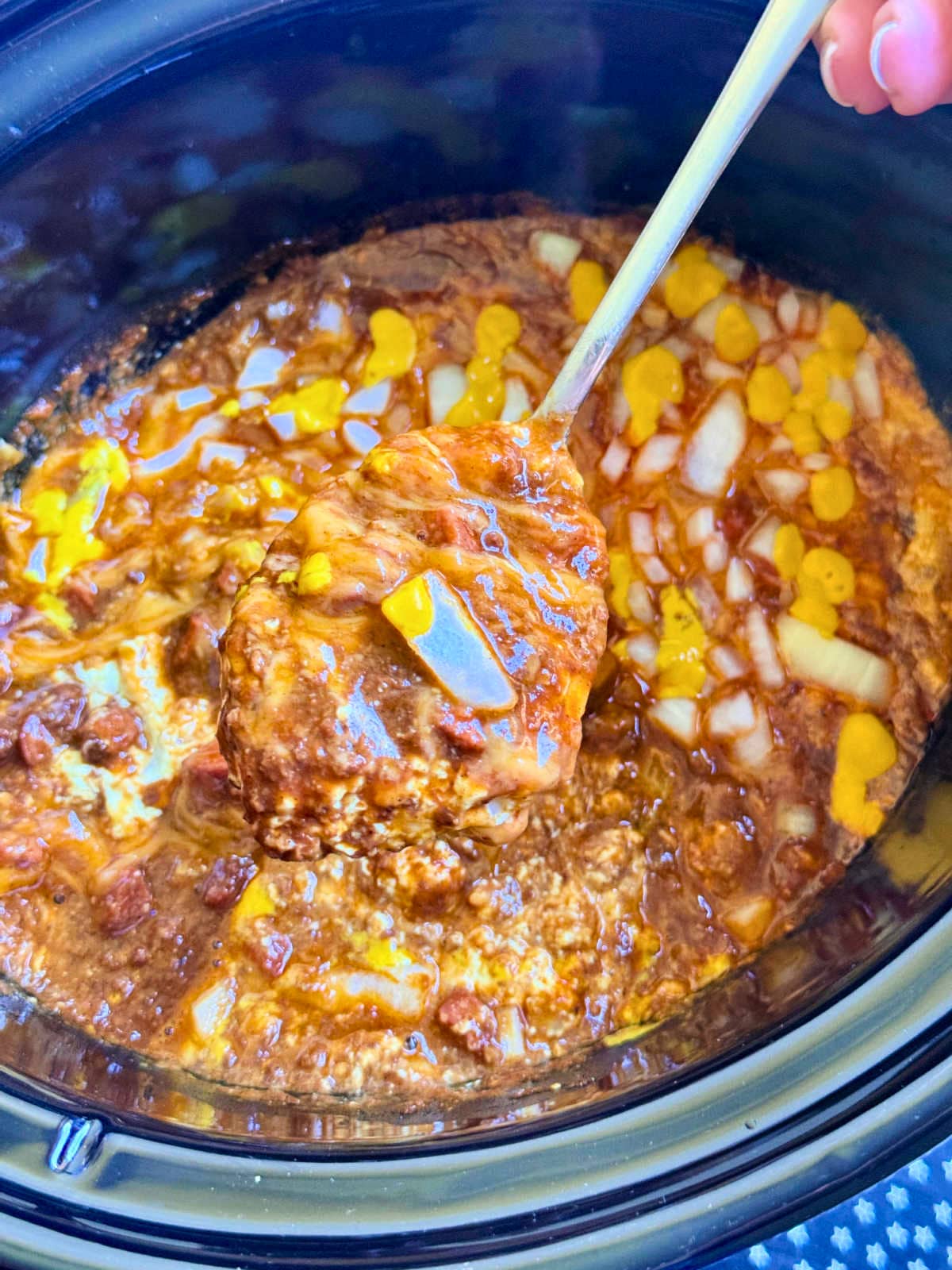 showing a spoonful of skyline dip being served from the slow cooker insert