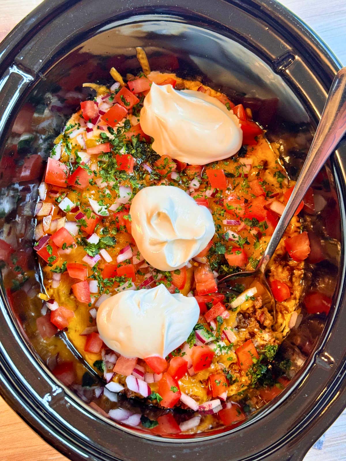 flat lay photo of crockpot insert with garnished taco dip inside